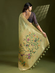 Woman holding a beige embroidered saree with floral patterns on a green background