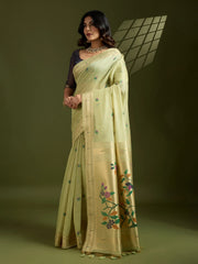 Woman wearing a light green saree with floral patterns on a dark background