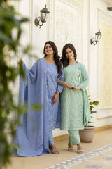 Two women in traditional outfits standing in a well-lit room with decorative elements.