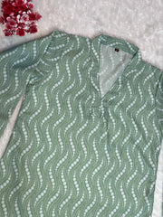 Green patterned shirt on a textured surface with red flowers in the corner
