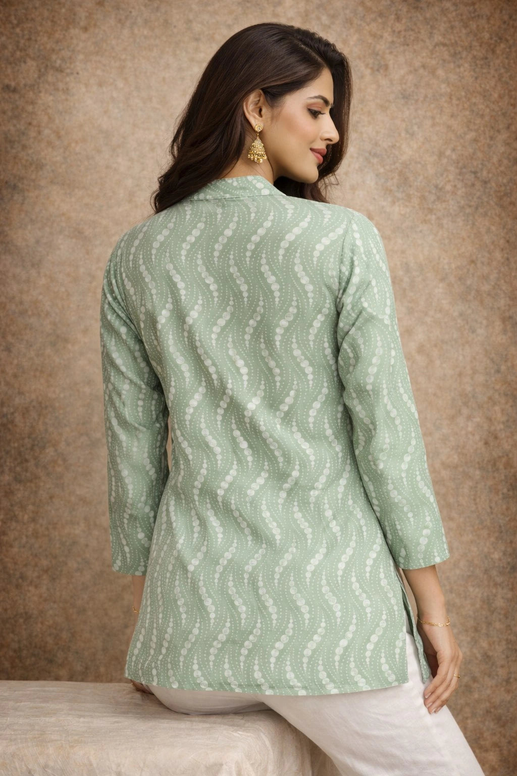 Woman wearing a light green patterned shirt against a brown background