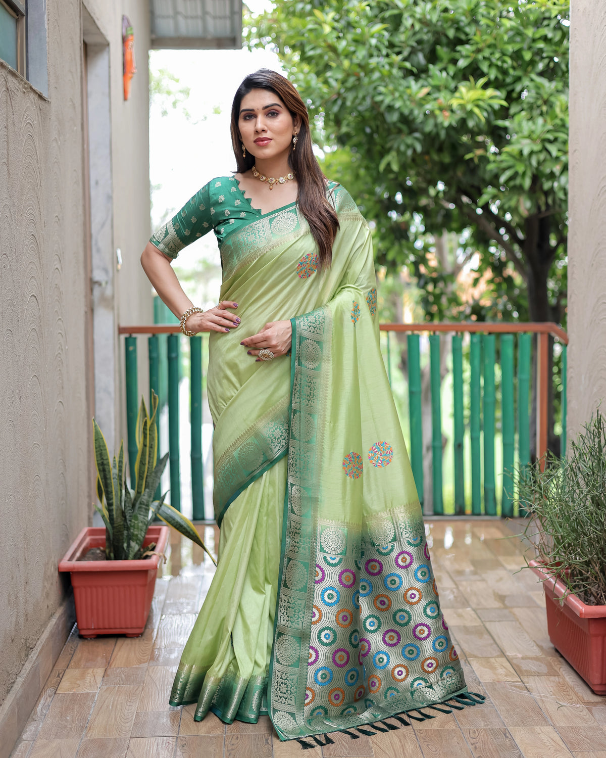 Woman wearing a green and white saree with a patterned border on a balcony.