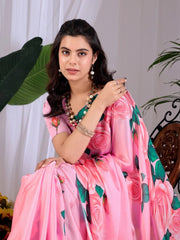 Woman wearing a pink saree with floral patterns against a white curtain background
