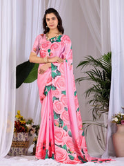 Woman wearing a pink saree with floral patterns in a decorated indoor setting.