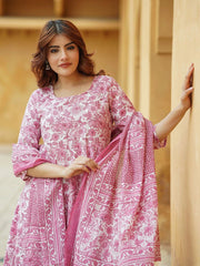 Woman wearing a pink and white patterned dress against a beige wall.