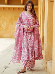 Woman wearing a pink and white traditional outfit with a matching dupatta against a beige wall.
