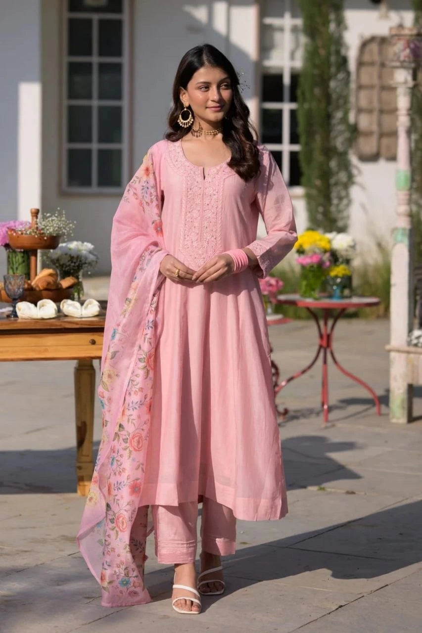 Woman in a pink traditional outfit standing outdoors with decorative elements.