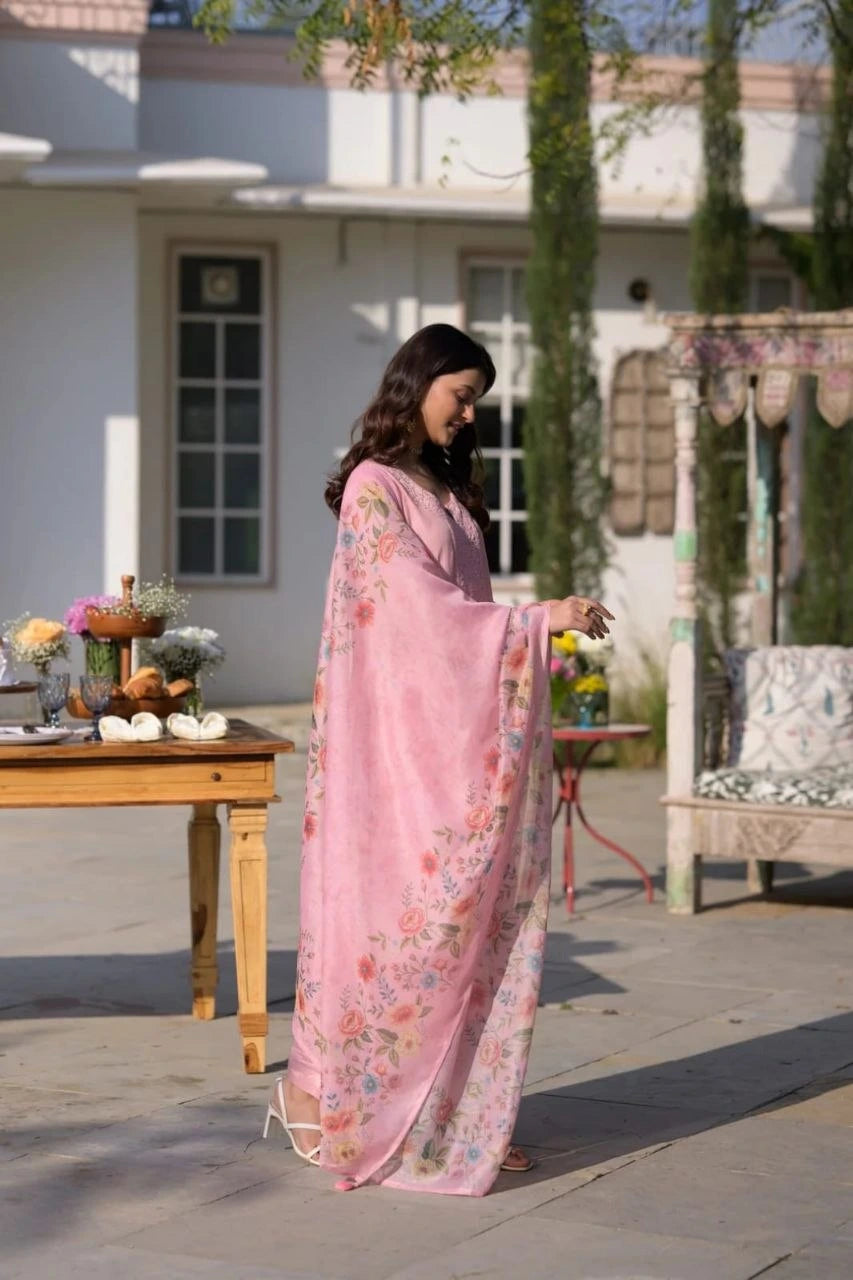 Woman in a pink floral saree standing outdoors on a patio.