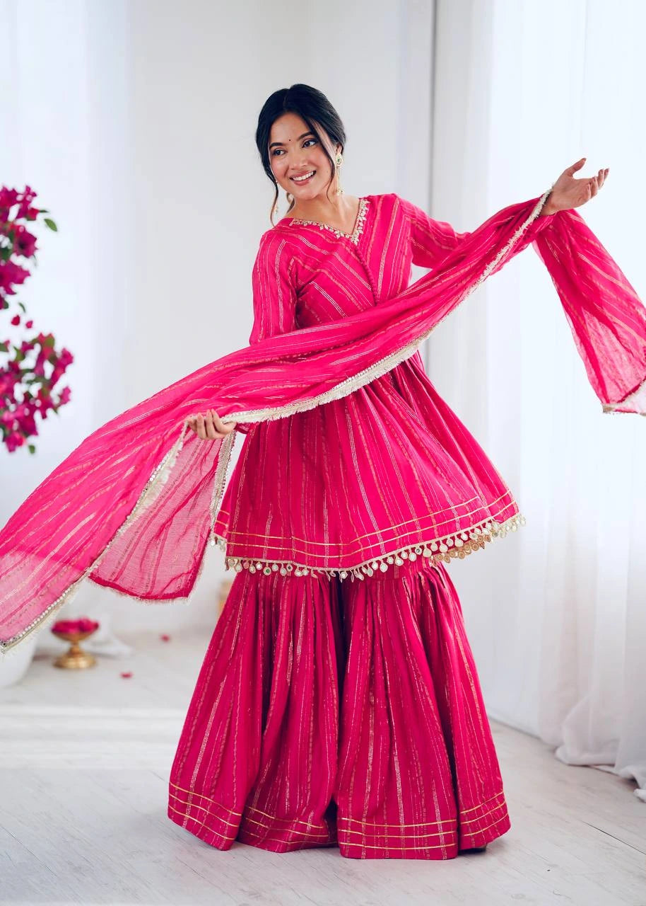 Woman in a bright pink traditional outfit with a matching dupatta, standing against a white background.