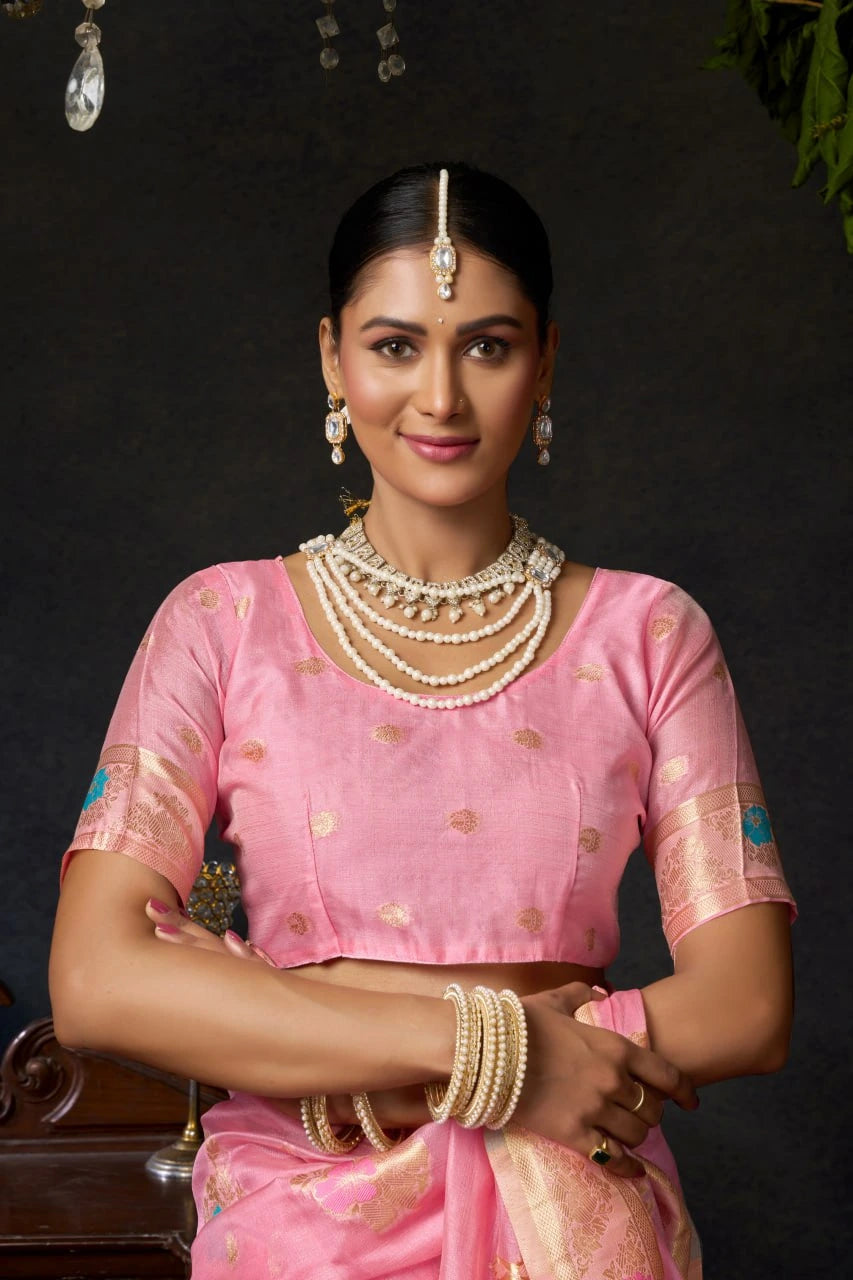 Woman in a pink saree with jewelry against a dark background