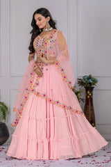 Woman in a pink traditional outfit with floral embellishments in an indoor setting.