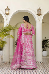 Woman in a pink traditional outfit standing in an archway with plants.