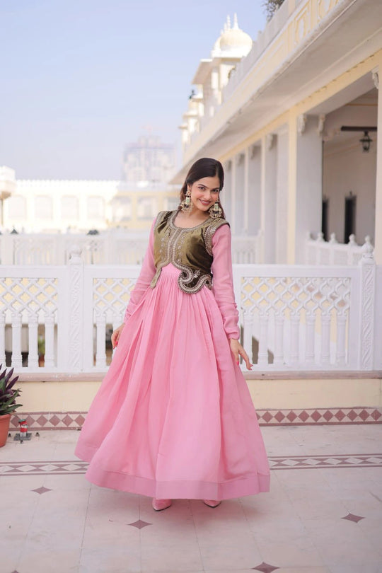 Woman in a pink traditional outfit standing in front of a white building with a blue sky.