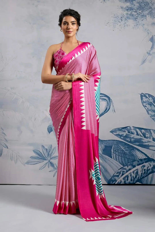 Woman wearing a pink saree with a white and blue pattern against a light gray background