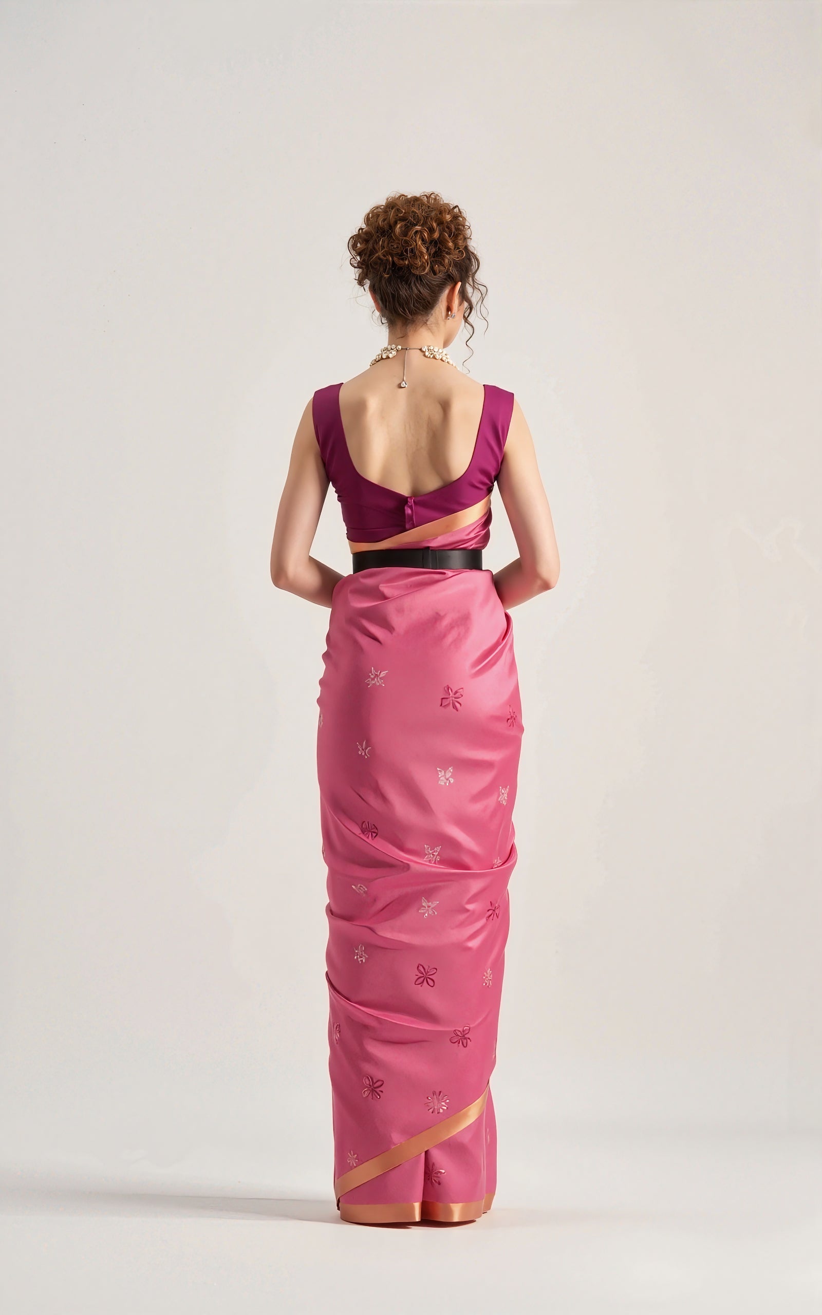 Woman wearing a pink saree with a cut-out design on a white background