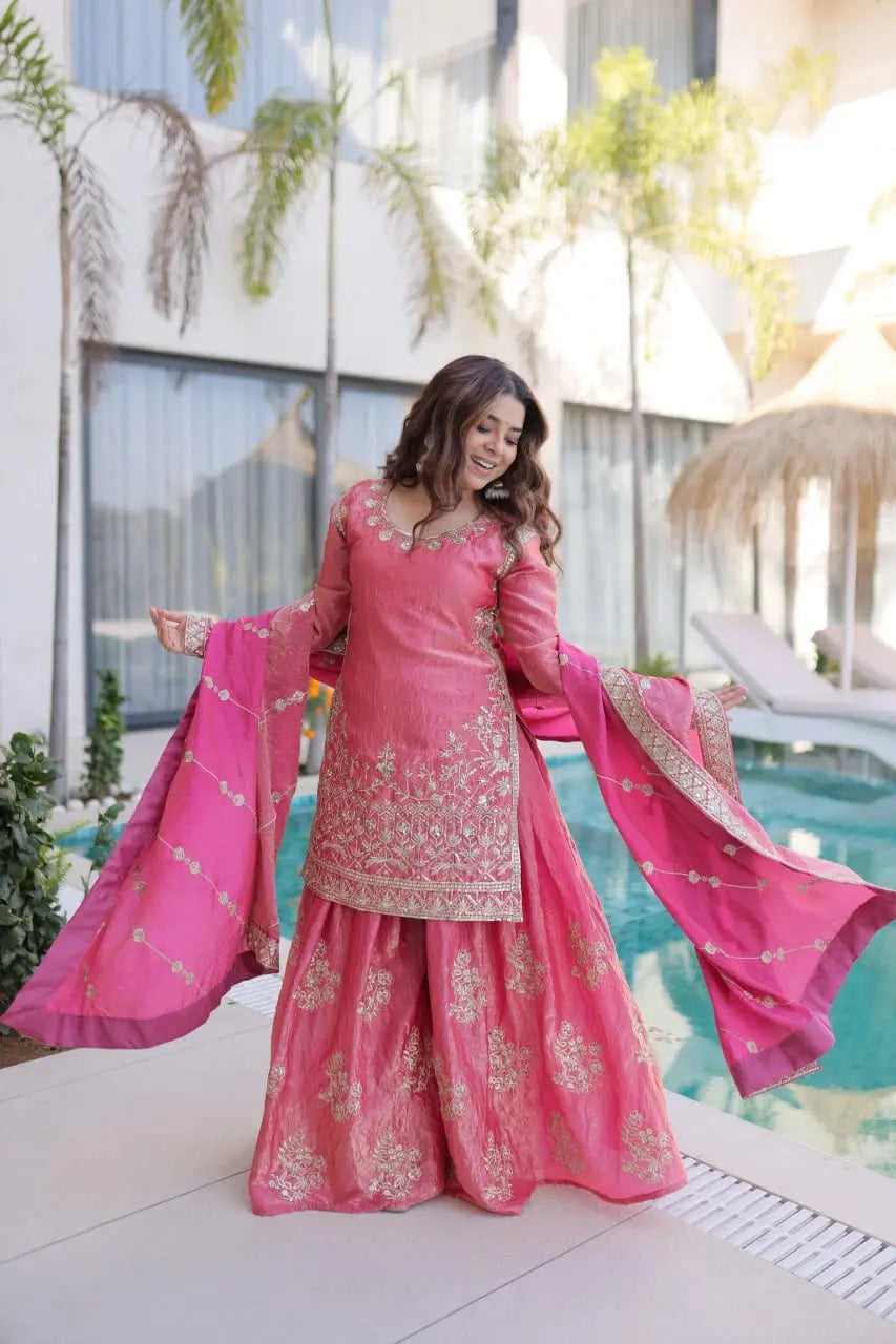 Woman in a pink traditional outfit standing by a poolside.