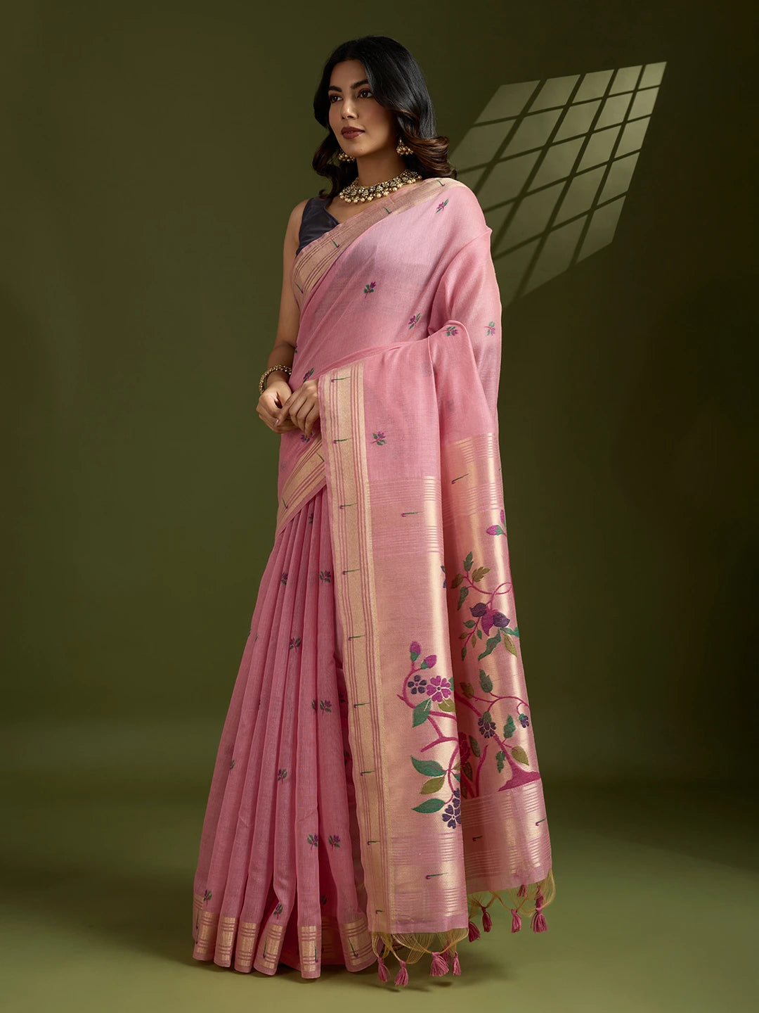 Woman wearing a pink saree with floral patterns on a green background