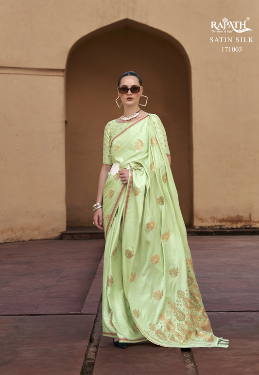 Woman wearing a light green saree with a traditional setting, featuring the Raphae brand.