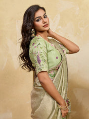 Woman wearing a green saree with floral patterns against a beige background