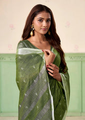 Woman wearing a green saree with a white border against a light background