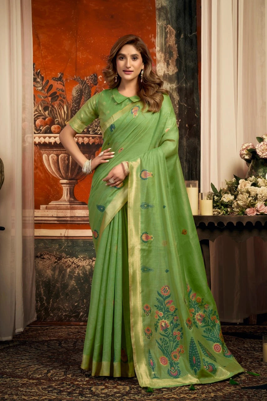 Woman wearing a green saree with floral patterns indoors.