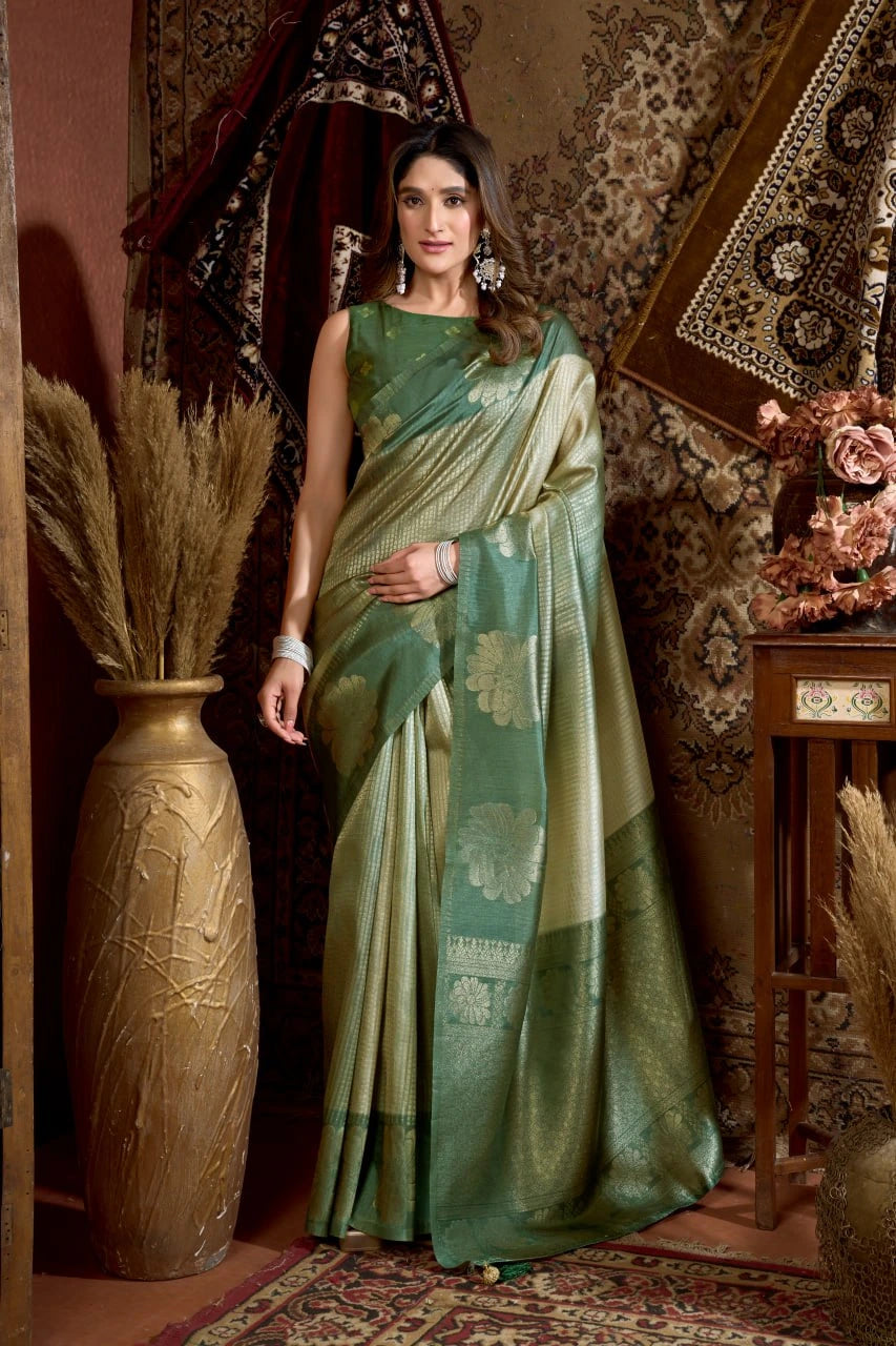 Woman in a green saree standing in an ornate room with decorative elements.