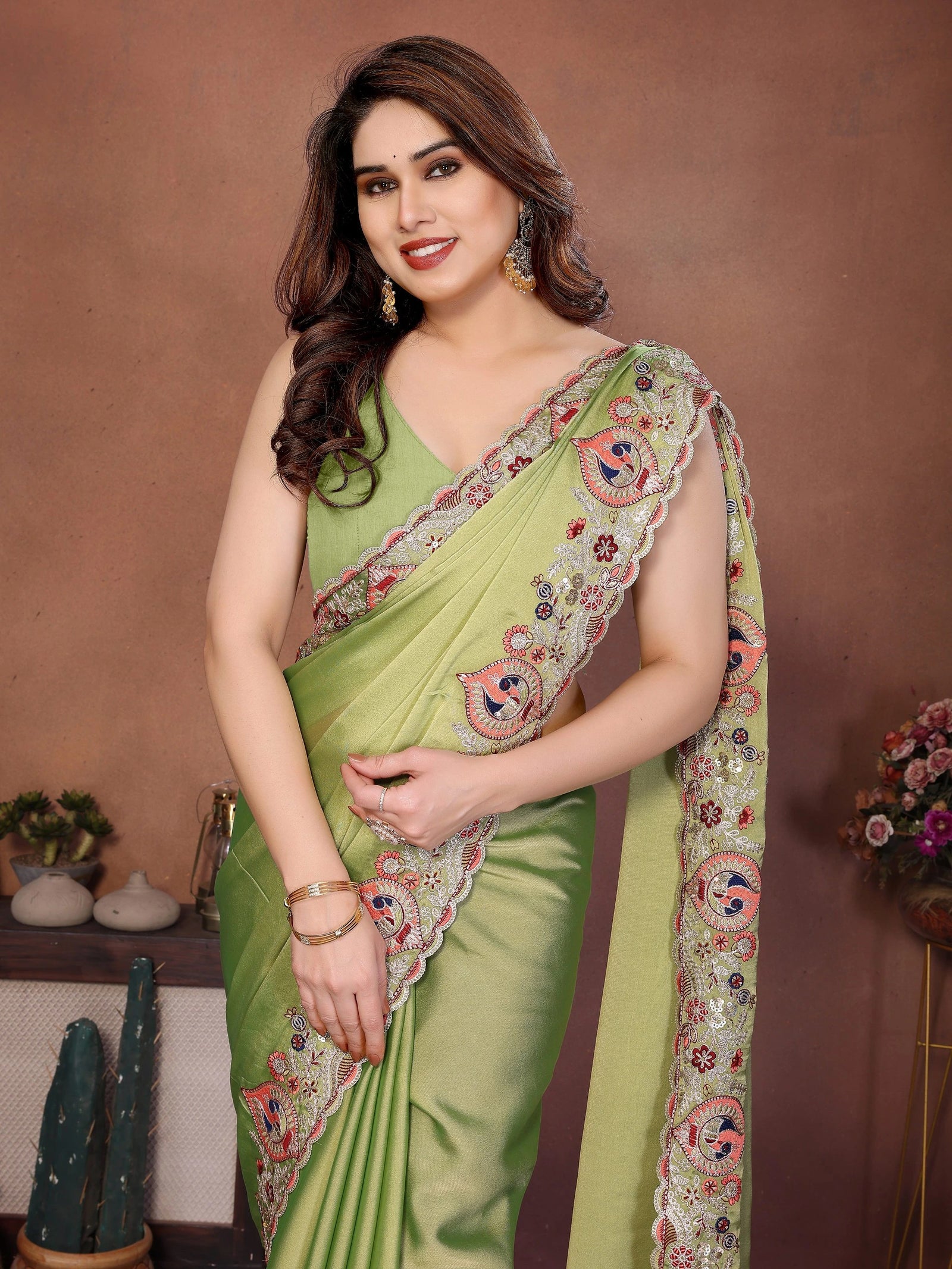 Woman wearing a green saree with floral patterns against a brown background