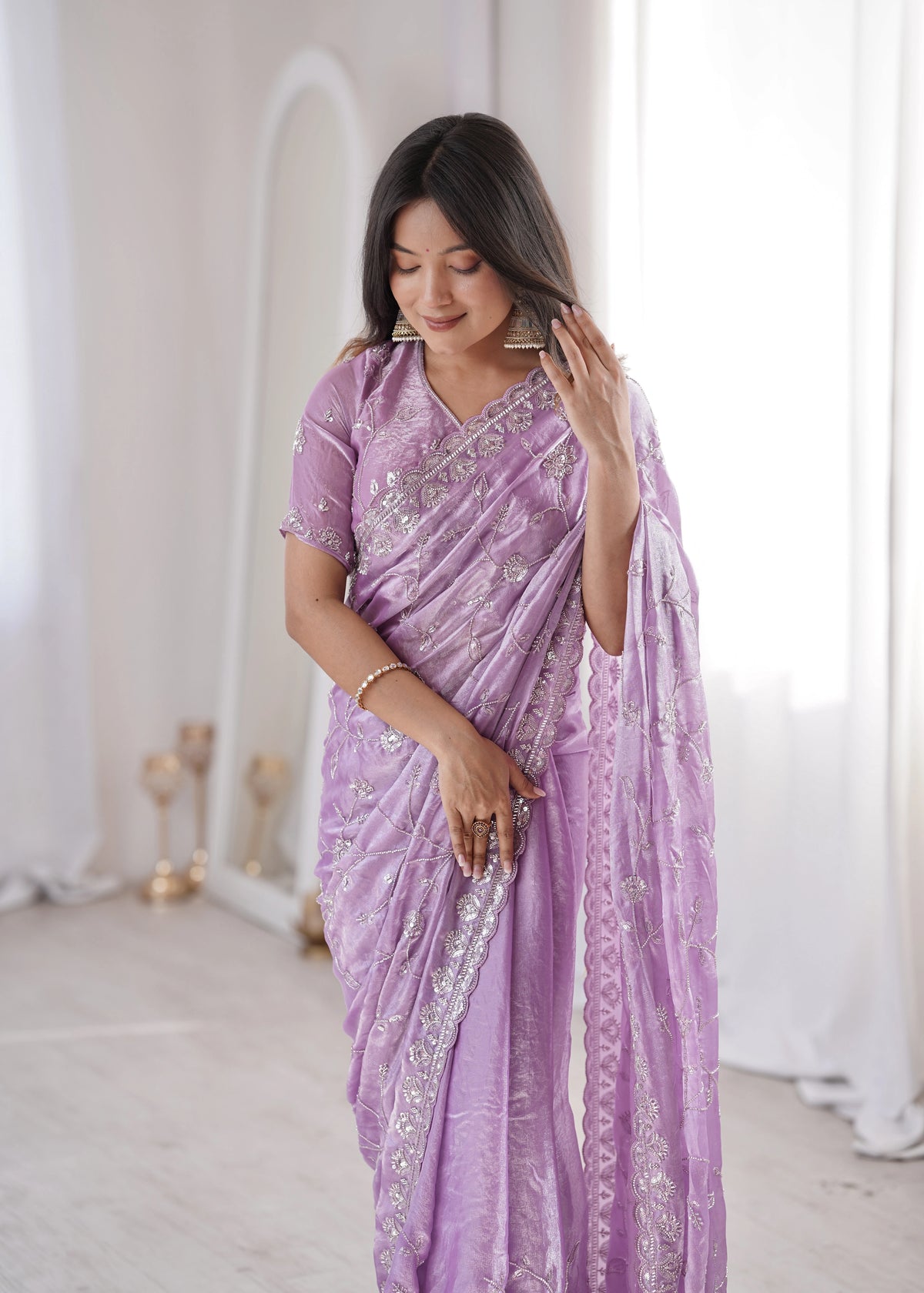 Woman wearing a purple saree with silver embroidery in a minimalistic setting.