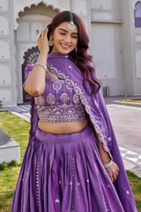 Woman in a purple traditional outfit with silver embroidery standing in front of a building.
