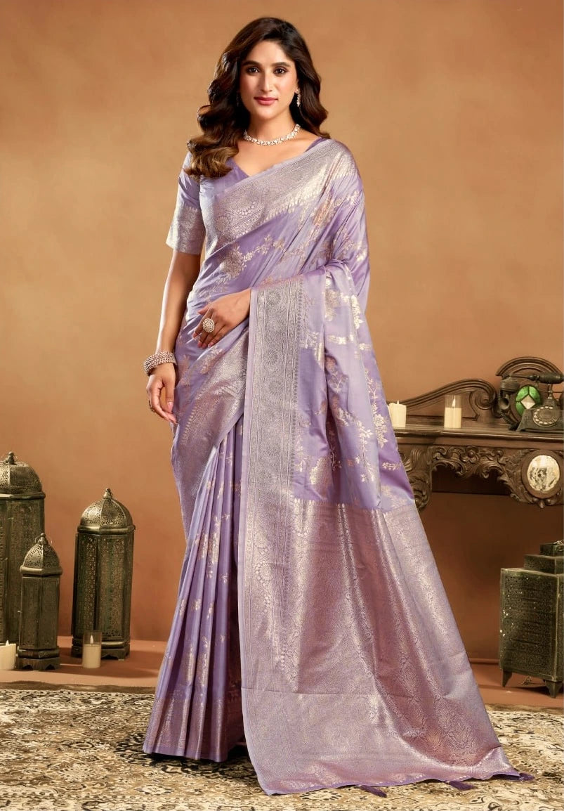 Woman wearing a lavender saree with a decorative pattern in an elegant indoor setting.