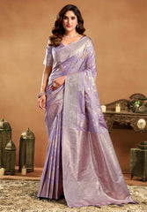 Woman wearing a lavender saree with a decorative pattern in an elegant indoor setting.