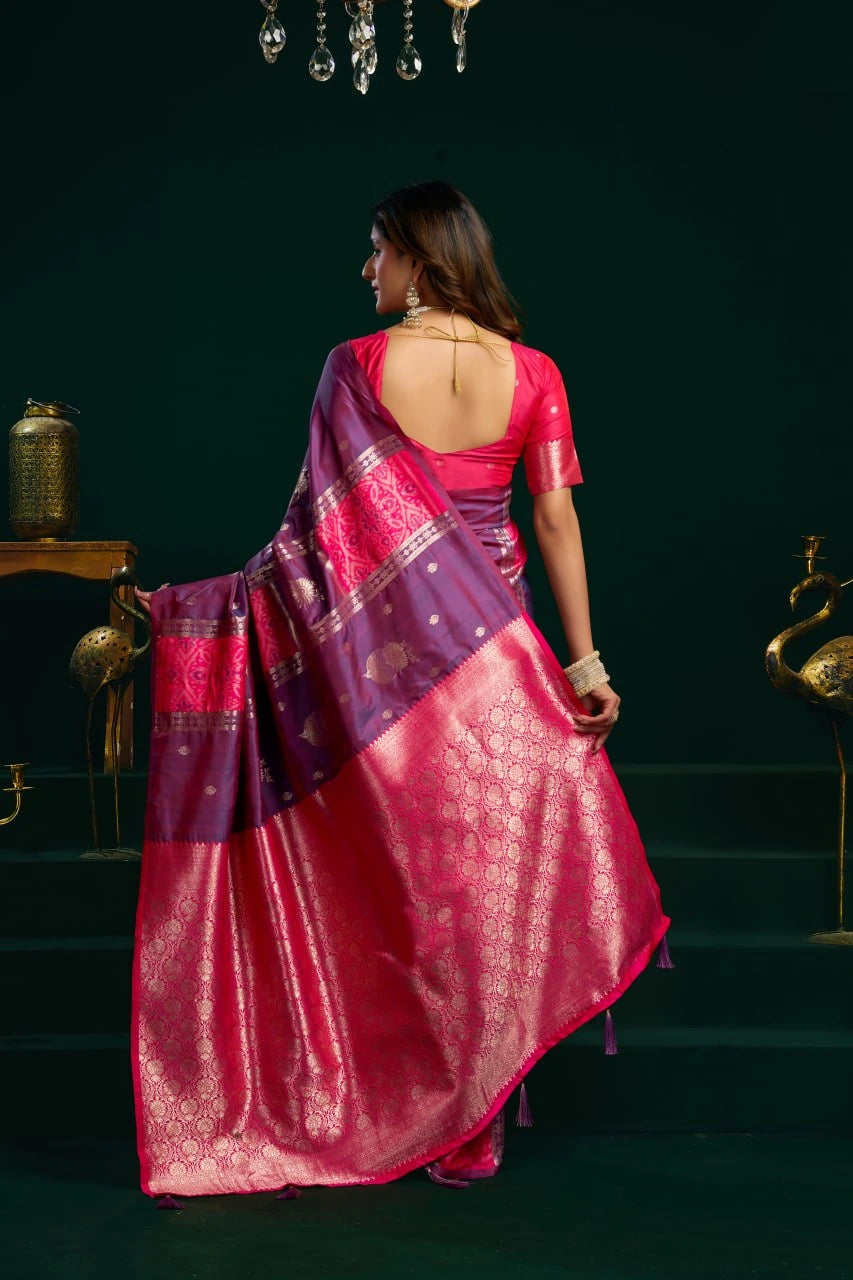 Woman in a pink and purple saree walking in a dimly lit room.