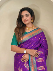 Woman wearing a purple saree with gold patterns against a neutral background