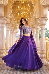 Woman in a purple traditional outfit standing in an ornate architectural setting.