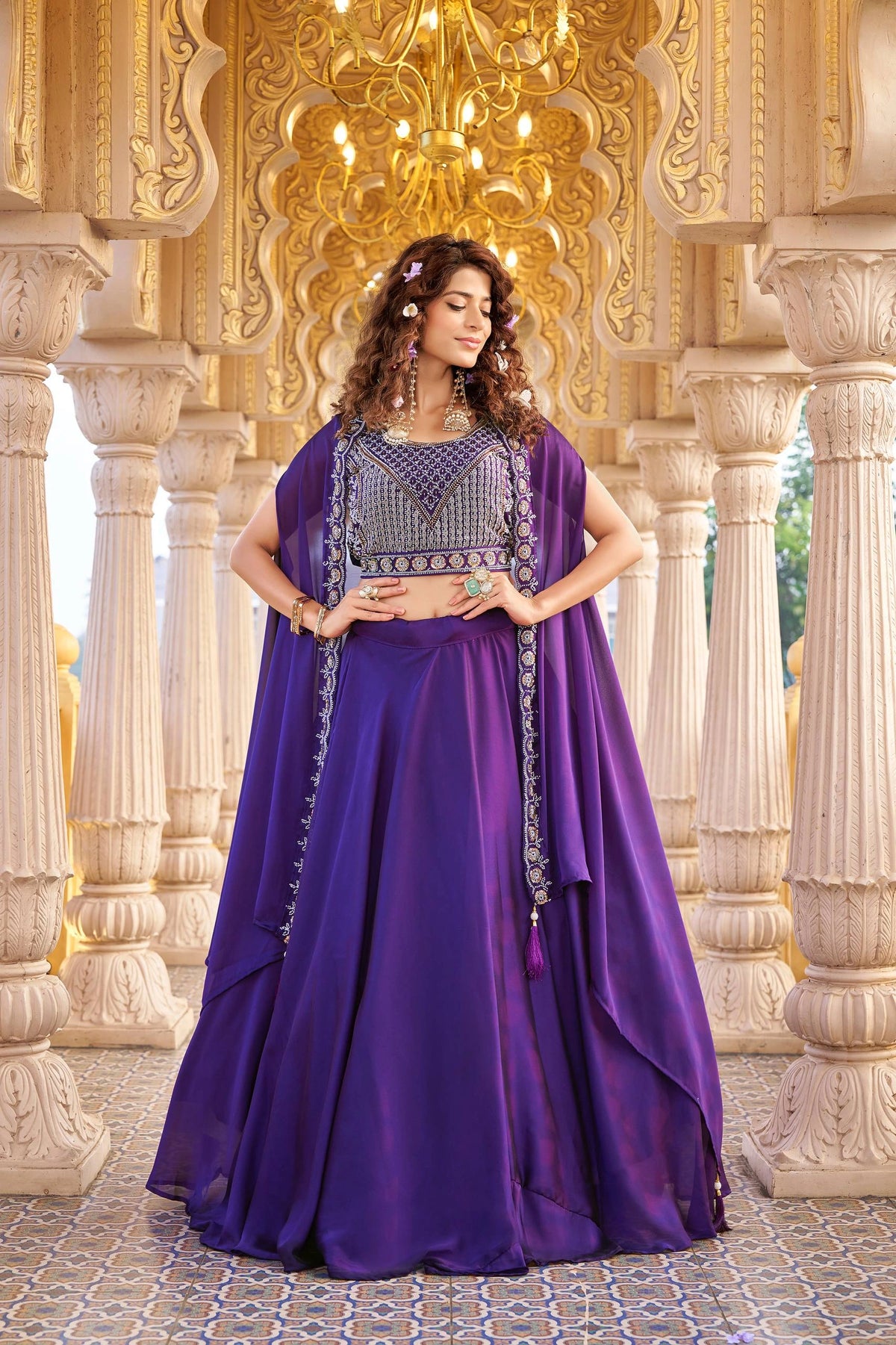 Woman in a purple dress with intricate detailing standing in an ornate architectural setting.