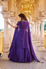 Woman in a purple dress with a cape standing in an ornate architectural setting.