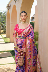 Woman in a colorful saree standing outdoors near architectural elements.