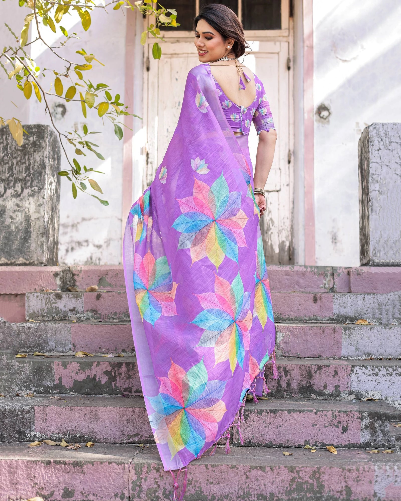 Woman in a colorful saree standing on steps outdoors