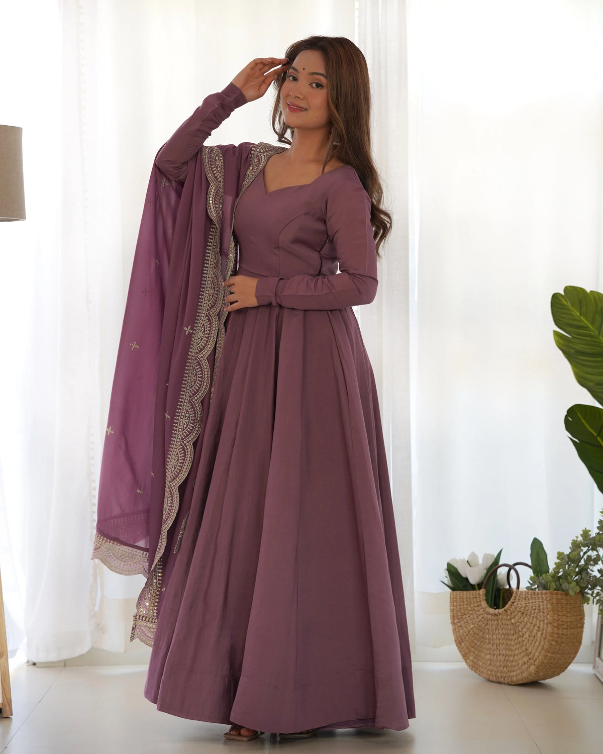 Woman in a long purple dress with a matching shawl standing indoors.