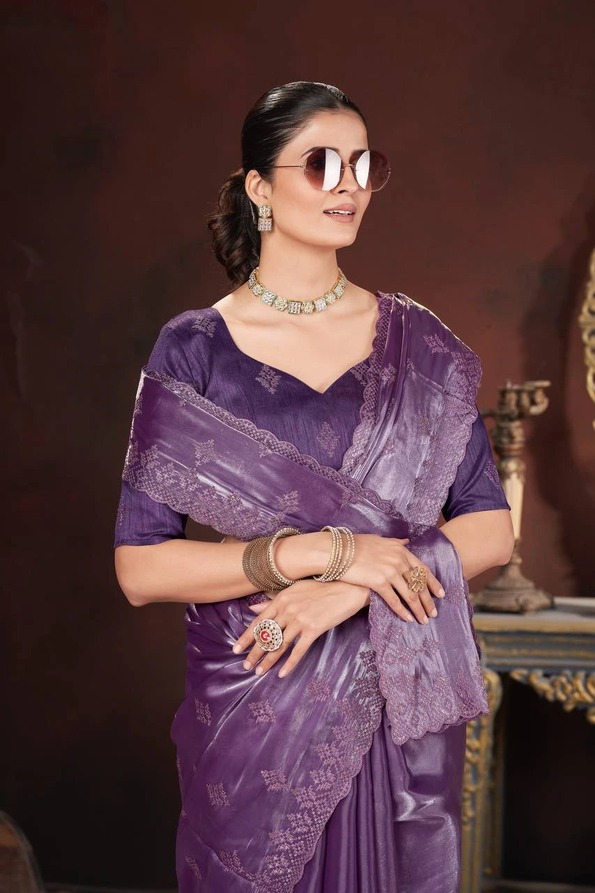 Woman wearing a purple saree with jewelry against a dark background