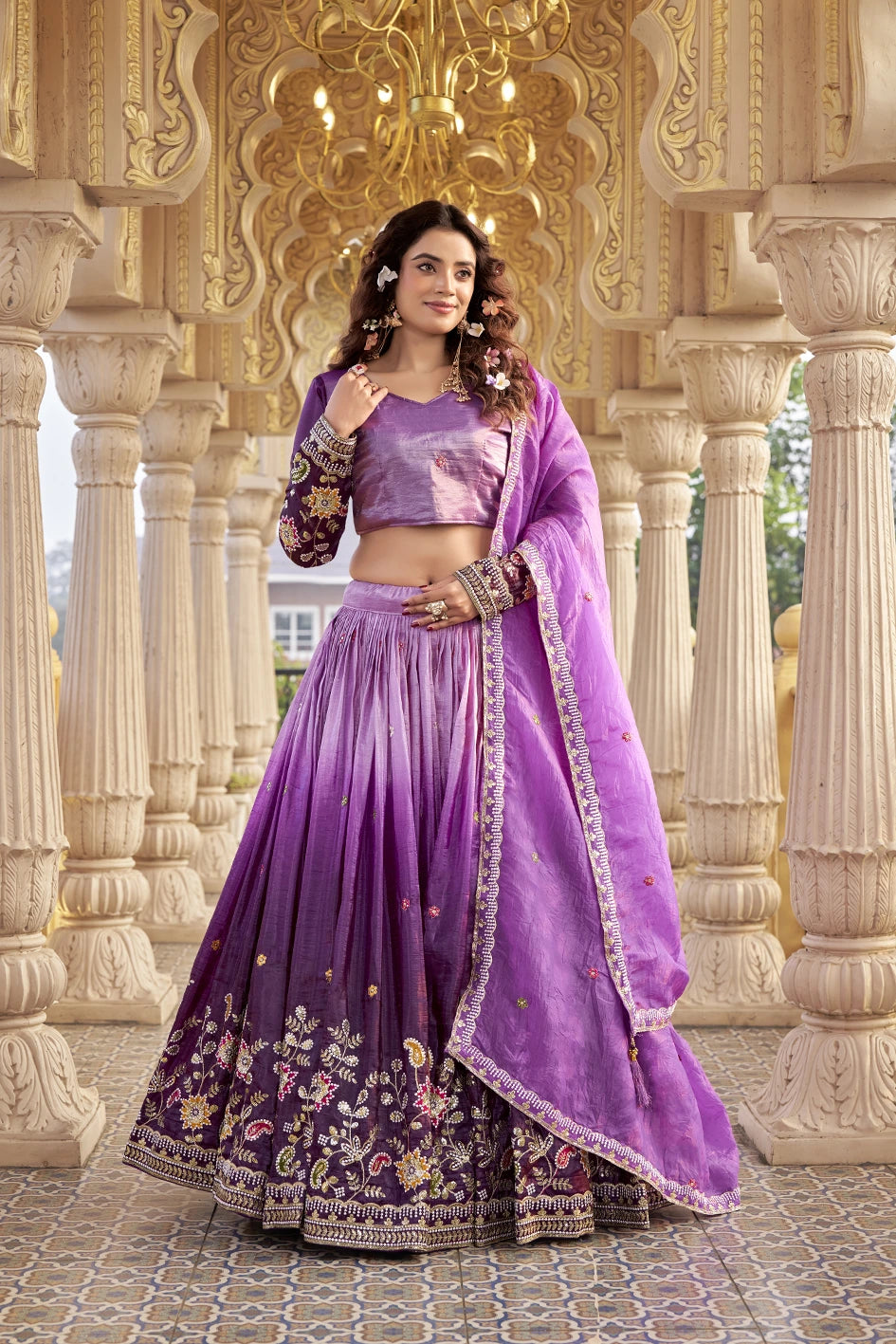 Woman in a purple traditional outfit standing in an ornate architectural setting.