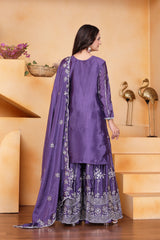 Woman wearing a purple traditional outfit with white embroidery in a decorative setting.