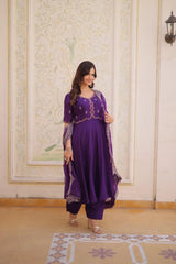 Woman wearing a purple traditional outfit with gold embroidery in an indoor setting.