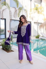Woman in a purple outfit standing by a pool with decorative plants and a building in the background.