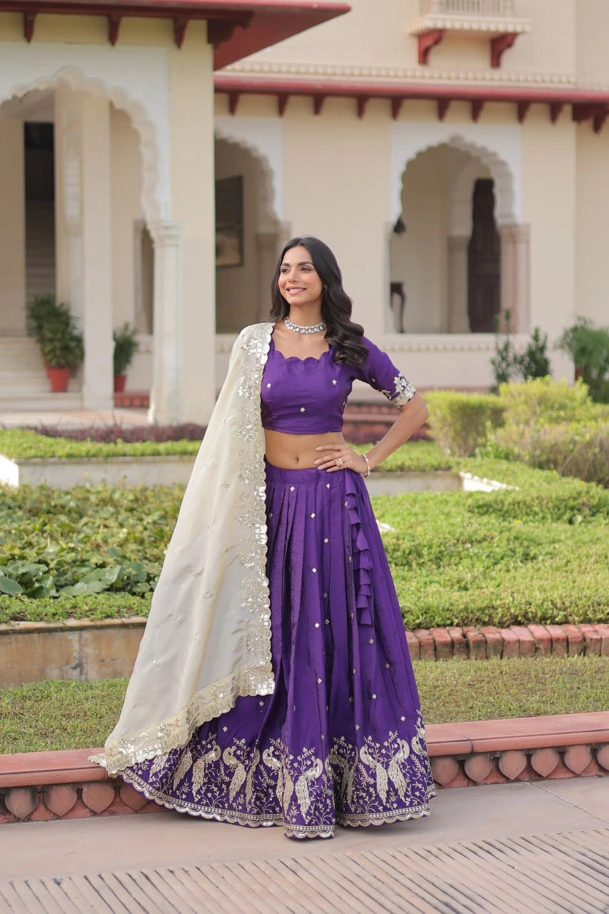 Woman in a purple traditional outfit standing in front of a building with greenery.