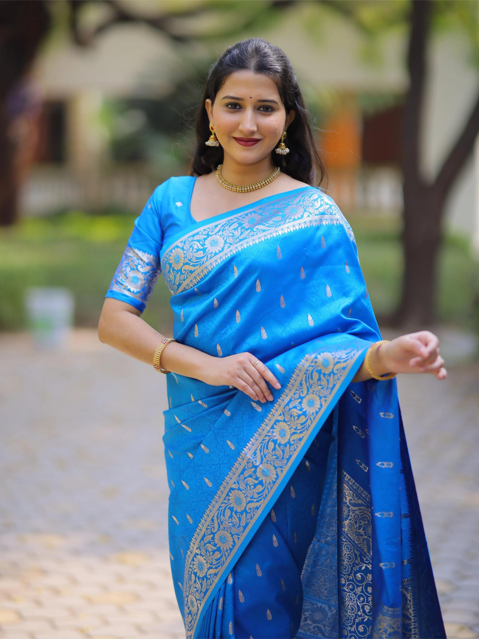 Woman wearing a blue saree with a blurred outdoor background