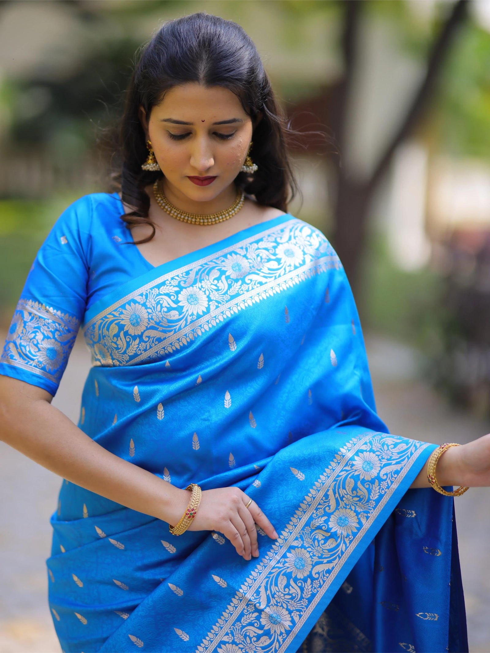 Woman wearing a blue saree with white patterns outdoors