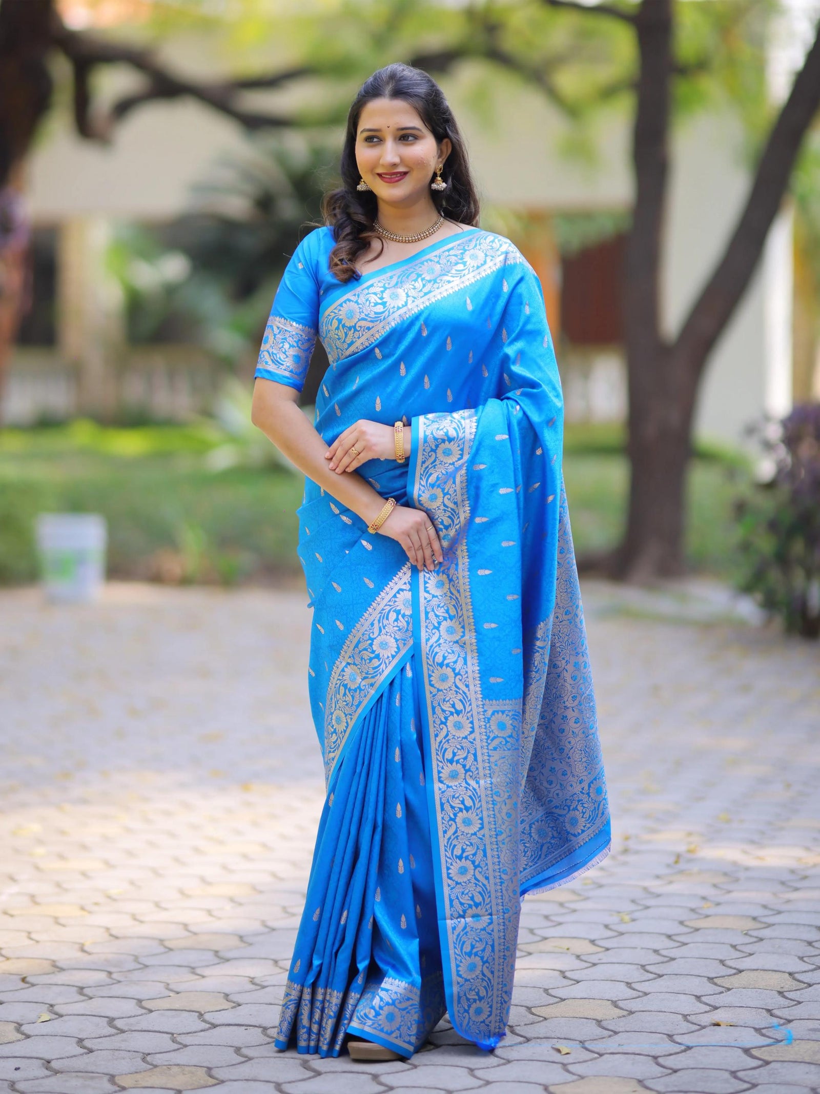 Woman wearing a blue saree with a white border outdoors.