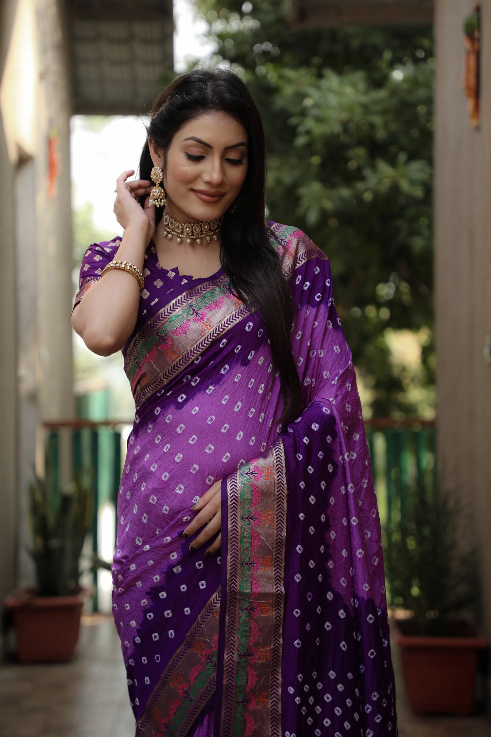 Woman in a purple saree with a blurred outdoor background