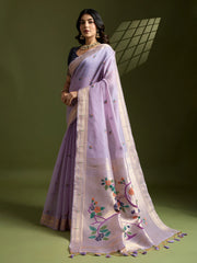 Woman wearing a light purple saree with floral embroidery on a green background